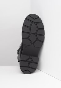 Černé kožené kotníkové boty s texturovanou gumovou podrážkou se geometrickým vzorem. Boční zip pro snadný přístup. Velikost 37.