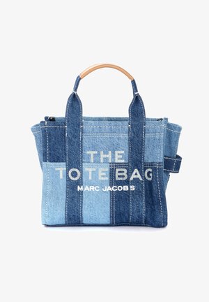 Geantă din denim cu un gradient de culoare albastră, având text alb care spune "THE TOTE BAG" și "MARC JACOBS," și mânere de tip lemn.