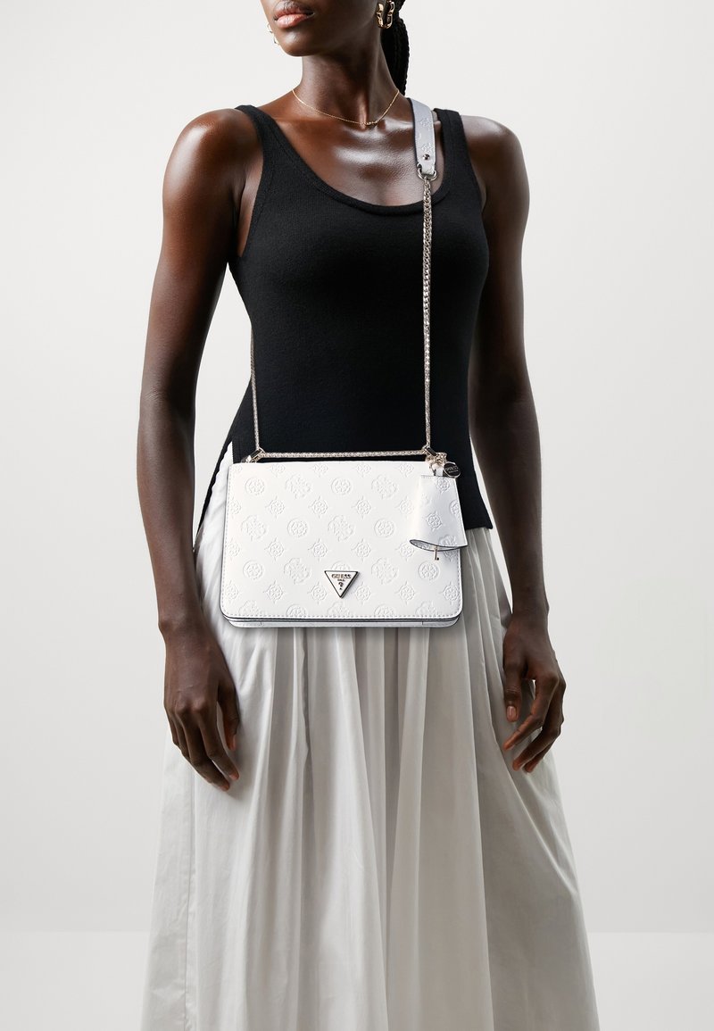 Bolso de hombro de cuero blanco con patrón en relieve y herrajes plateados. Cuenta con una correa de cadena y una pequeña etiqueta desmontable.