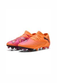 Scarpe da calcio Puma con un design che sfuma dall'arancione al rosa, tomaia testurizzata, sistema di allacciatura e suola nera con tacchetti colorati.