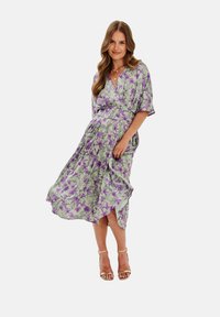 Kvetinové šaty s krátkymi rukávmi v svetlej zelenej farbe s fialovými kvetmi. Má výstrih do V a voľný sukňový strih so bočným rozparkom. Nosí sa s sandálmi na viazanie.