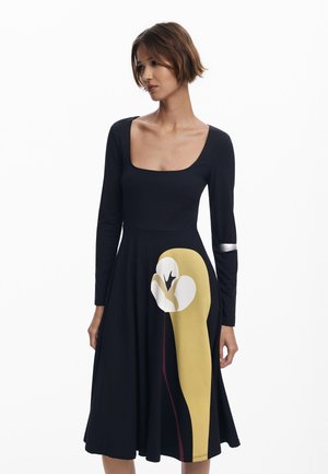 Schwarzes langärmeliges Kleid mit quadratischem Ausschnitt, das auf dem Rock mit einem großen abstrakten Blumenmuster in Gelb, Weiß und Burgunderrot verziert ist.