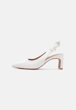 Hvid læder slingback-pumpe med spids tå, rynket elastikrem og blokhæl mod en ensartet lysegrå baggrund.