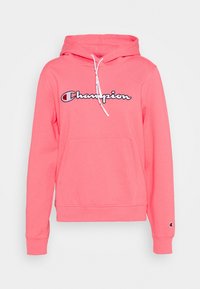 Sweat à capuche rose avec poche avant, cordon de serrage sur la capuche, et logo "Champion" en blanc et noir sur la poitrine. Texture de tissu douce.
