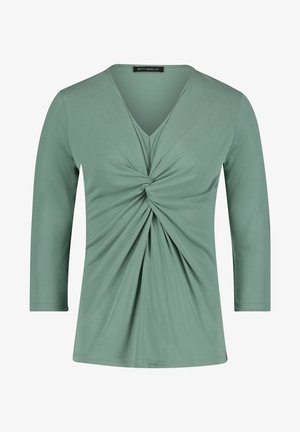 Light green long-sleeve top with a V-neck and twisted front detail, made from a smooth, stretchy fabric. Clean, streamlined design.