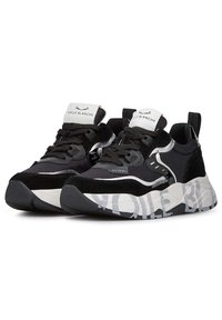 Sneaker nere con parte superiore in suede e sintetico, con logo bianco sulla linguetta, suola testurizzata e motivo astratto grigio e bianco sulla suola esterna.