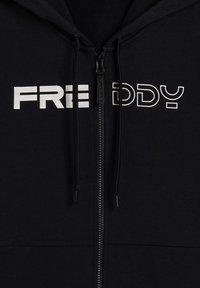 Haut de hoodie noir zippé avec le texte imprimé en blanc "FREDDY" sur le devant. Comprend des cordons de serrage, une texture lisse et une coupe classique.