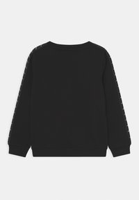 Sweat-shirt noir avec manches longues, encolure ronde et motifs décoratifs le long des coutures d'épaule. Le tissu semble doux et texturé.