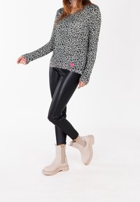Leopard print long-sleeve top in gray, paired with black faux leather leggings and beige ankle boots with elastic side panels.