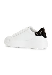 Sneakers bianchi in pelle con suola spessa bianca. Tallone in suede nero con borchie dorate. Punta arrotondata e design lacci piatti.