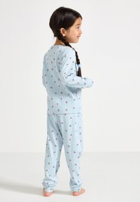 Ensemble de pyjama pour enfants de couleur bleu clair avec une texture côtelée. Motif de cerises rouges. Comprend des manches longues et un pantalon à taille élastique.
