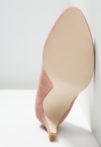 Chaussure à talon haut pointu en daim rose unique vue de la semelle avec une semelle extérieure beige clair et un petit talon carré.