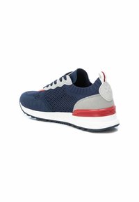 Zapatilla deportiva en azul marino y gris con parte superior de malla, entresuela blanca, línea de acento roja y pestaña trasera texturizada. Presenta cordones redondos y un diseño elegante.