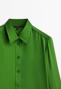 Chemise boutonnée à manches longues de couleur vert vif avec un col pointu, vue de face sur un fond blanc.