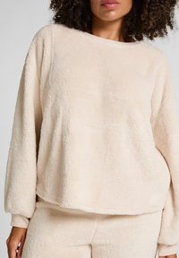 Crème-kleurige fleece sweatshirt met een ontspannen pasvorm, lange mouwen en ribgebreide manchetten. Zachte textuur met een gezellige uitstraling.