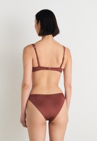 Hnědá bikiny souprava se jednoduchým designem, nastavitelnými ramínky a háčkovým zapínáním. Hladký povrch tkaniny a vysoký vykrojený spodní díl.