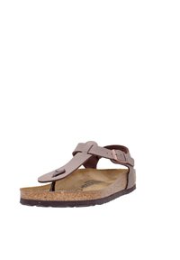 Sandale en cuir marron avec une semelle en liège, boucle métallique ajustable et semelle texturée. La sandale présente un design minimaliste.