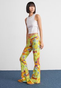 Farebné rozšírené nohavice s tie-dye vzorom v žltej, oranžovej a fialovej farbe. Mäkka tkanina s elastickým pásom a jemným logom.