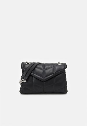 Czarna pikowana skórzana torebka na ramię z kopertową klapą oraz srebrnym łańcuchem i skórzanym paskiem na jednolitym jasnym tle.