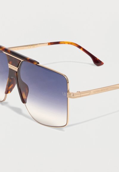 Γυαλιά ηλίου με μεγάλα τετράγωνα φακούς σε μπλε διαβάθμιση, χρυσό μεταλλικό σκελετό και άκρα βραχίονα με σχέδιο χελώνας, επωνυμίας Victoria Beckham.