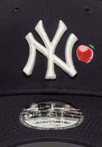 Μπλε σκουρό μπέιζμπολ καπέλο με κεντημένο λευκό λογότυπο "NY" και κόκκινο λογότυπο μήλου. Διαθέτει ρυθμιζόμενο λουράκι και στρογγυλεμένη γείσο.