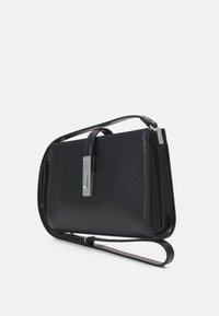 Sorte læderhåndtaske med flad form, justerbar skulderrem og sølvfarvet hardware. Har en elegant lukning og en glat overflade.