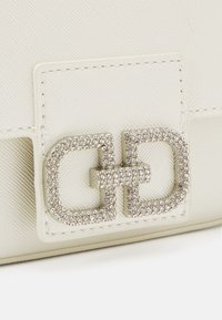 Weiße strukturierte Handtasche mit einem auffälligen Verschluss aus silberfarbenem Metall, der mit funkelnden Strasssteinen im doppelten 'G'-Design verziert ist.