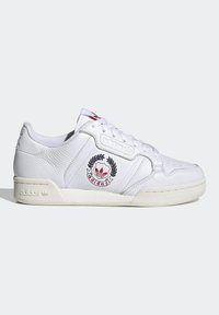 Sneaker bianco in pelle con tomaia testurizzata, chiusura con lacci e logo ricamato rosso e nero. Presenta una suola in gomma color crema e accenti sottili.