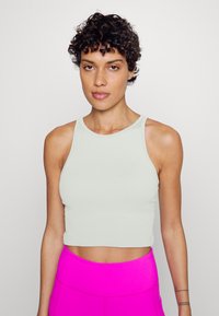 Top cropped cinza claro feito de tecido canelado, apresentando um decote redondo e um design sem mangas. Combinado com leggings rosa brilhante de cintura alta.