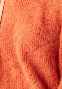Suéter de punto naranja suave con una textura peluda, que presenta un diseño acanalado y ligeras variaciones de tonalidad a lo largo de la tela.