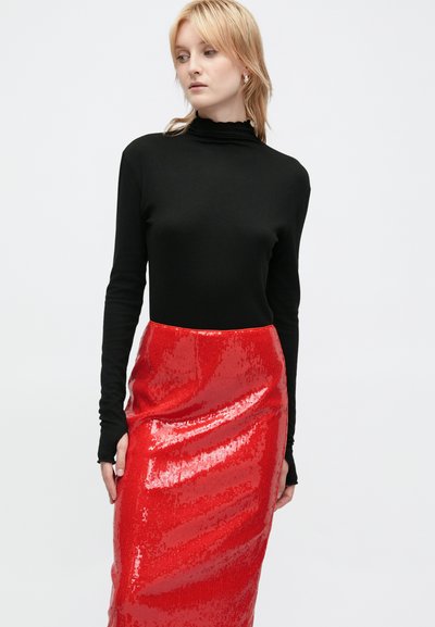 Un haut à manches longues noir à col chevalier associé à une jupe en sequins rouges jusqu'aux genoux, présentant une texture lisse et une surface brillante.