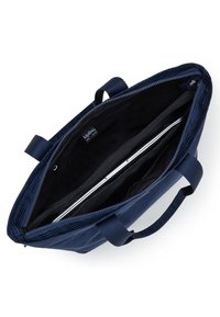 Mörkblå Kipling-toteväska med dubbla handtag, öppen dragkedja som avslöjar en vadderad laptopfack med en silverfärgad laptop inuti.