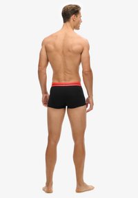Boxers noirs avec une taille rouge, conception ajustée, texture douce et longueur mi-cuisse. Unis sans motifs ou accents supplémentaires.
