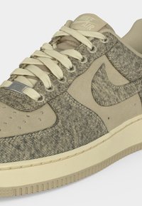 Μπεζ και κρεμ αθλητικό παπούτσι Nike Air με υφασμάτινα πάνελ με υφή, κορδόνια σε κρεμ απόχρωση, διατρητή μύτη και λεπτομέρειες από καουτσούκ στη σόλα.