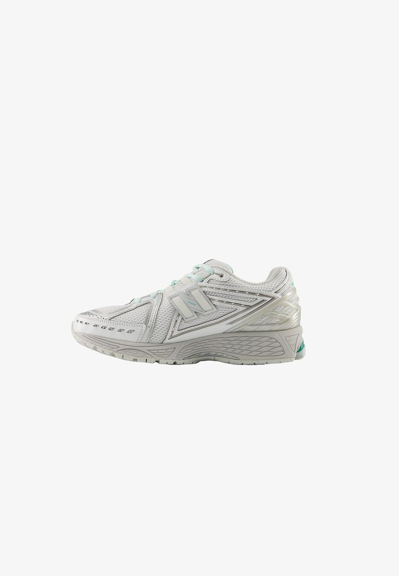 Chaussure de running New Balance blanche et grise avec des panneaux en mesh et une semelle texturée, vue de côté sur fond blanc.