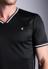 Camisa atlética negra de manga corta con un patrón texturizado de panal, diseño de cuello en v y rayas de acento blancas en el cuello y las mangas.