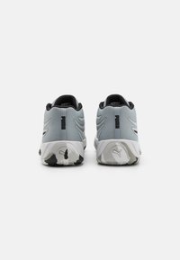 Grey athletic shoes with a textured mesh upper, black trim, and white soles featuring a patterned grip. Logo at heel and side.