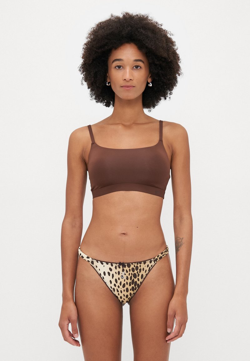 Brassière marron, sans coutures, avec de fines bretelles, associée à un bas de bikini beige à imprimé léopard avec un détail nœud sur le côté.
