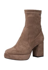 Bottine en daim beige avec une texture lisse, un talon bloc et une semelle compensée. Présente des surpiqûres sur les côtés et un design à bout arrondi.