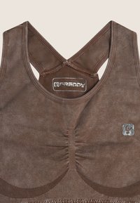 Reggiseno sportivo marrone con spalline incrociate, tessuto testurizzato, dettaglio arricciato al centro e accenti in argento.