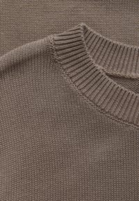 Pull en maille brun clair avec un col rond côtelé et une surface texturée. Présente une texture lisse et douce ainsi que des détails de couture réguliers.