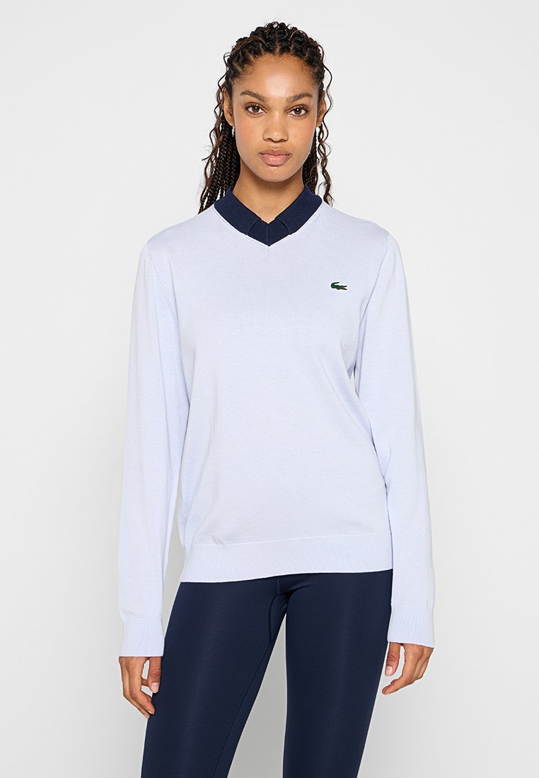 Hellblaues V-Neck-Pullover-Sweatshirt mit navyblauem Kragen; hat lange Ärmel und ein kleines grünes Logo auf der linken Brust.