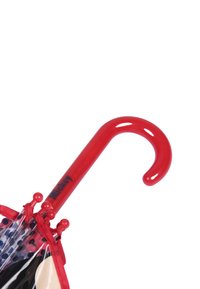 Manico di ombrello curvo rosso con finitura lucida, dotato di un'etichetta di testo nera. Copertura trasparente con pois neri e rifinitura rossa.