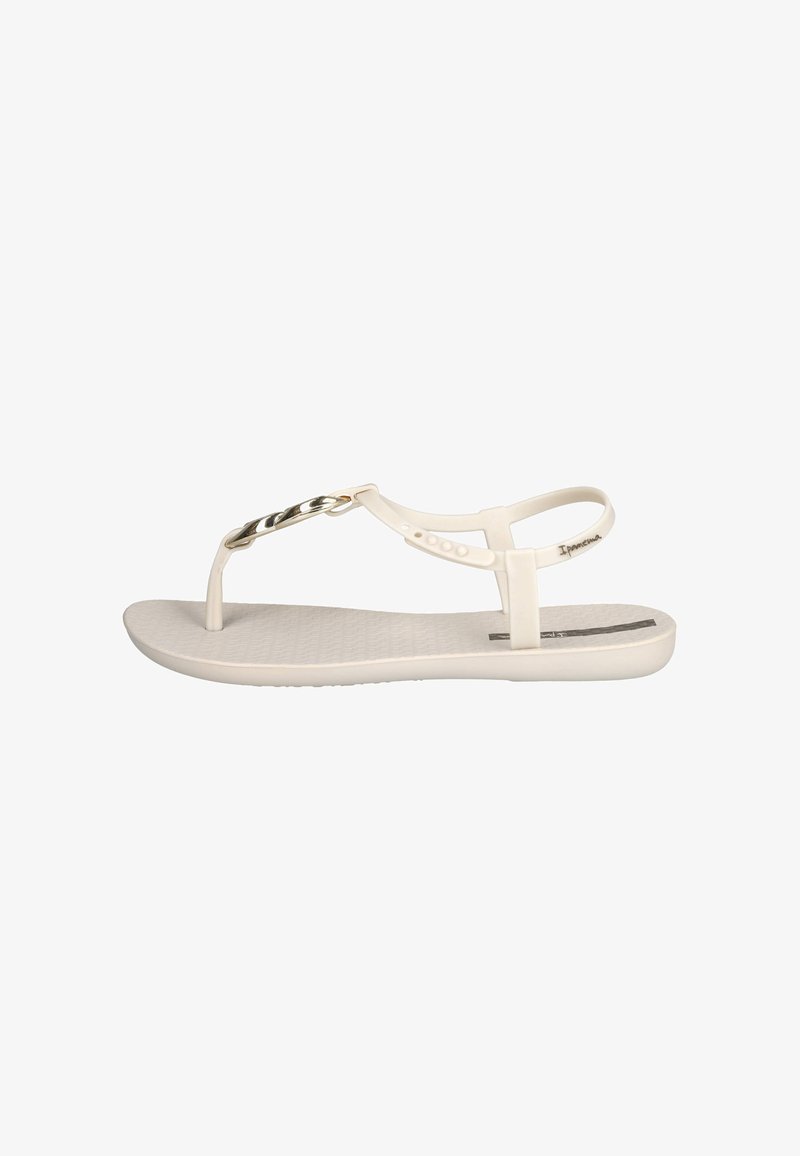 Sandalias tipo thong blancas con una plantilla texturizada, tiras delgadas y un acento de cadena dorada en la parte superior. Suela plana con un diseño minimalista.