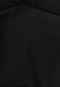 Černá prošívaná látka s hladkou strukturou, zdobená vzorem diamantových prošívek a jemným leskem. Bez výrazných kovových prvků nebo ozdob.