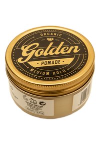 Lata de metal dorada con una etiqueta negra. La etiqueta presenta "Pomada Dorada", "Sujeción Media" y un gráfico de diamante. Tamaño: 100 ml.