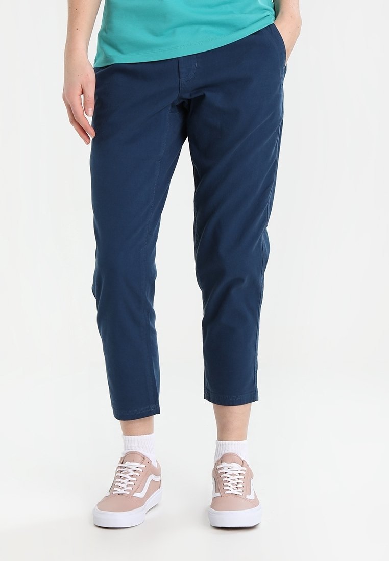 Granatowe chinosy o dopasowanym kroju, z krótką długością, wykonane z gładkiej mieszanki bawełnianej. Połączone z beżowymi trampkami i białymi skarpetkami za kostkę.