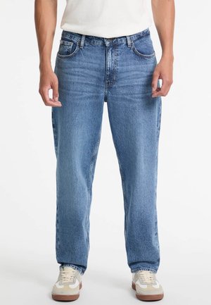 Lichtblauwe denim jeans met een recht model, vijf zakken en subtiele vervaging. Gepaard met meerkleurige sneakers.