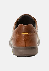 Braune Ledersneaker mit strukturiertem Finish, abgerundetem Absatz, dezenten Nähten und einem gelben Akzent hinten. Gummisohle.