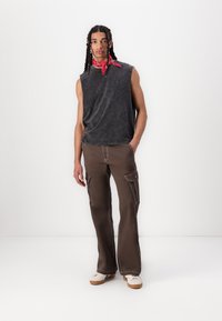 Sleeveless gray T-shirt with a faded look, paired with brown cargo pants featuring side pockets, and tan sneakers with a textured outsole.